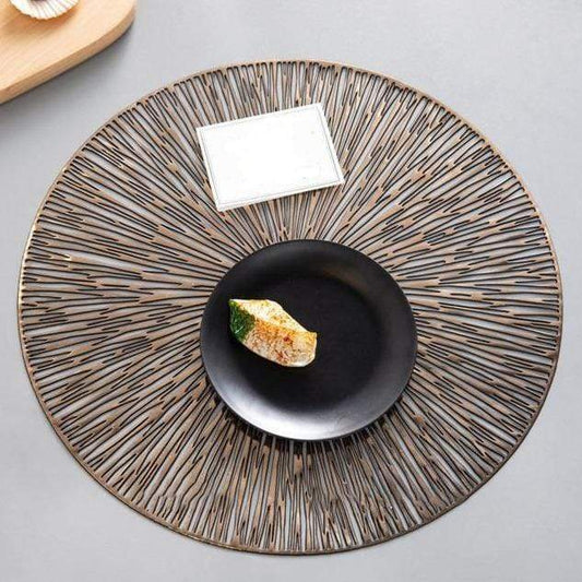 Round woven placemat with a black plate and a piece of bread on a gray surface