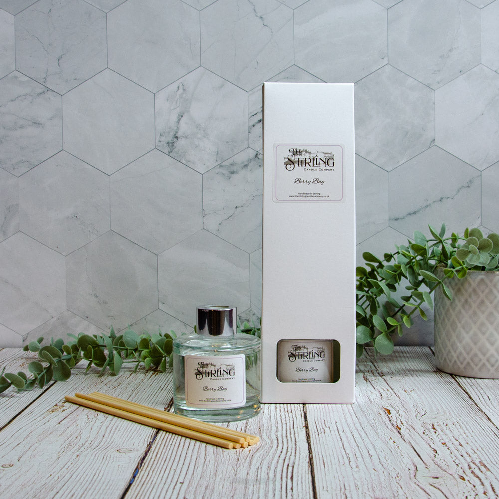 Berry Bay diffuser with packaging and sticks on a wooden surface with a marble wall background