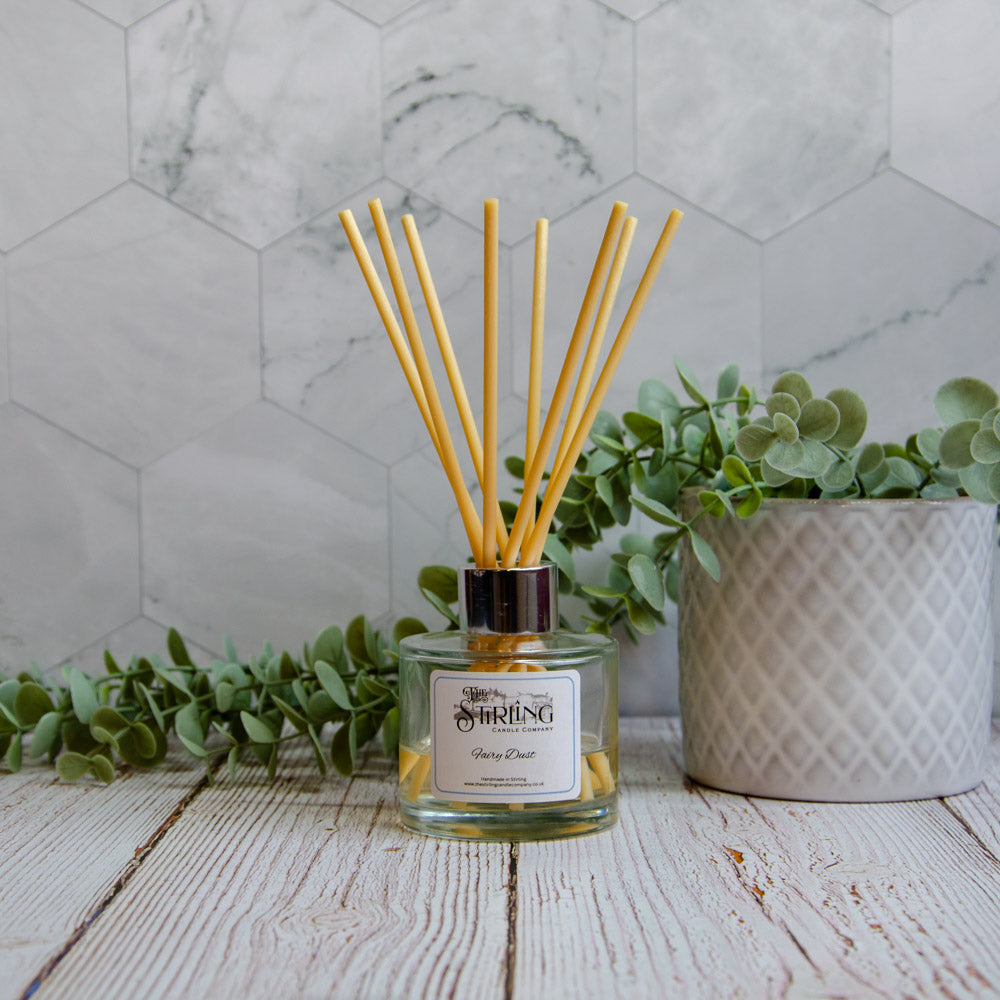 Reed diffuser with eucalyptus leaves on a wooden surface with a marble wall background