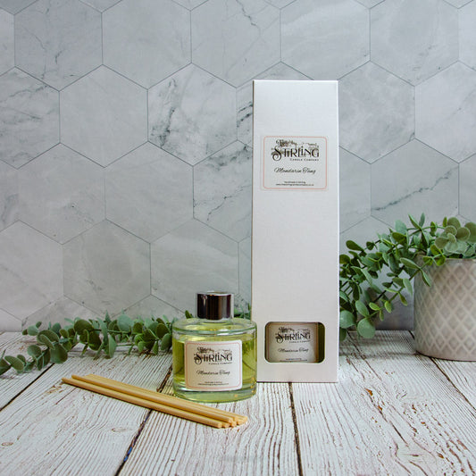 Diffuser bottle and packaging on a wooden surface with a marble wall background